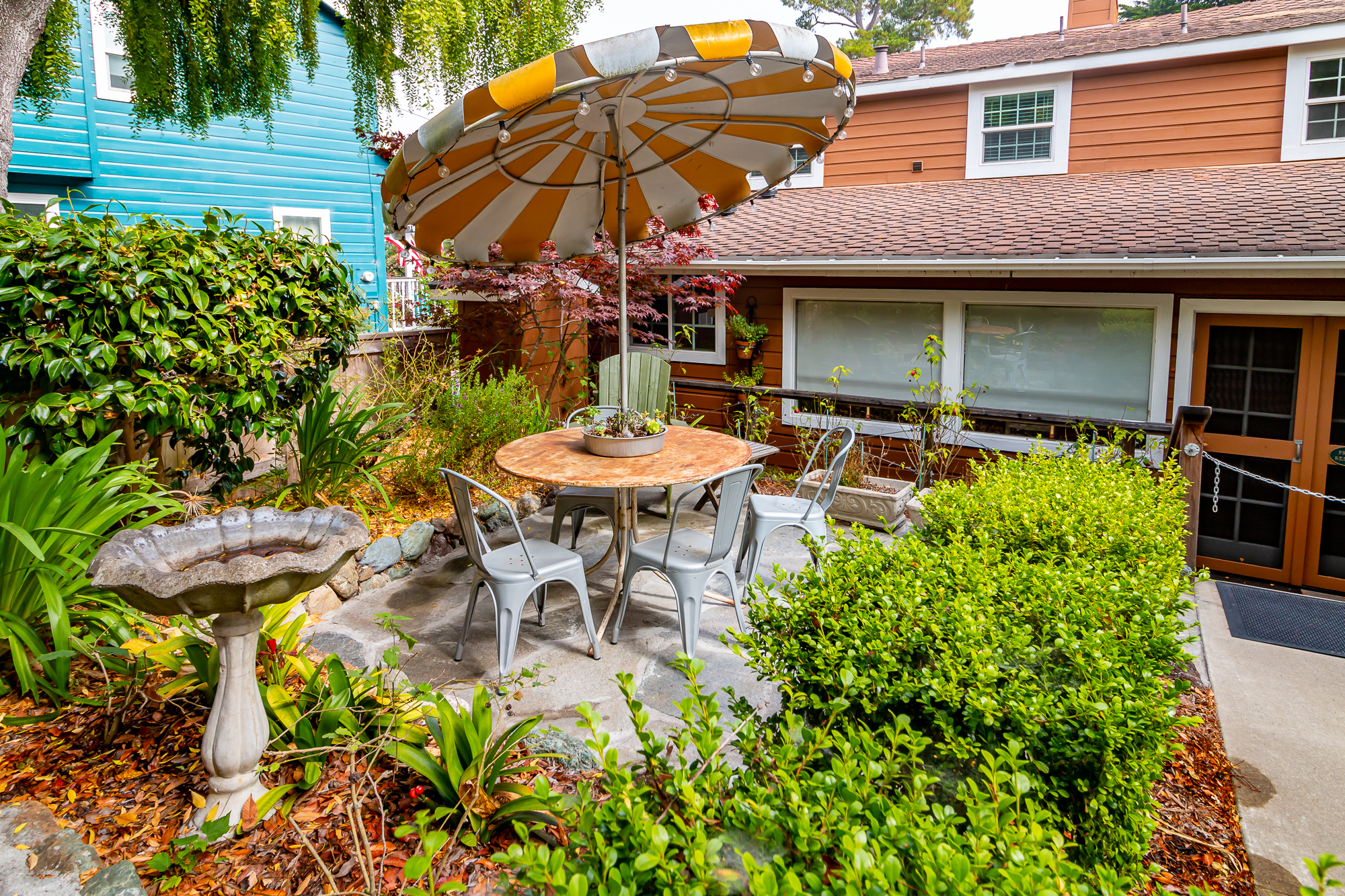 a small outdoor patio with a table and chairs under an umbrella
